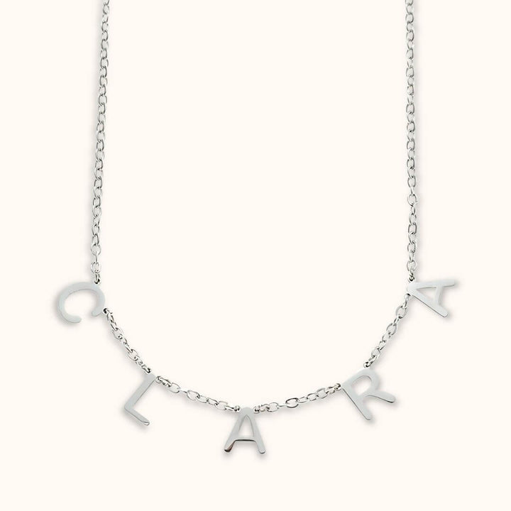 Silver personalized letter name necklace with dainty charm letters spelling 'Clara,' ideal for everyday wear.