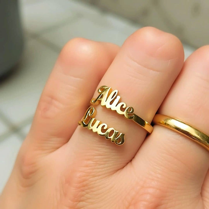 Close-up of a gold double name ring with 'Alice' and 'Lucas' engravings, ideal for personalized jewelry lovers