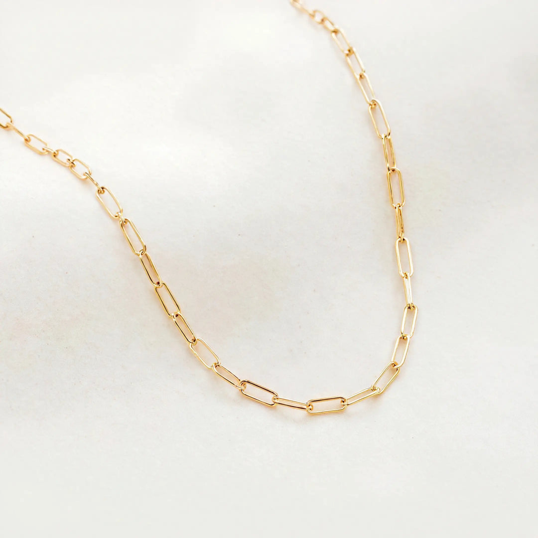 Gold chain necklace on a light gray background