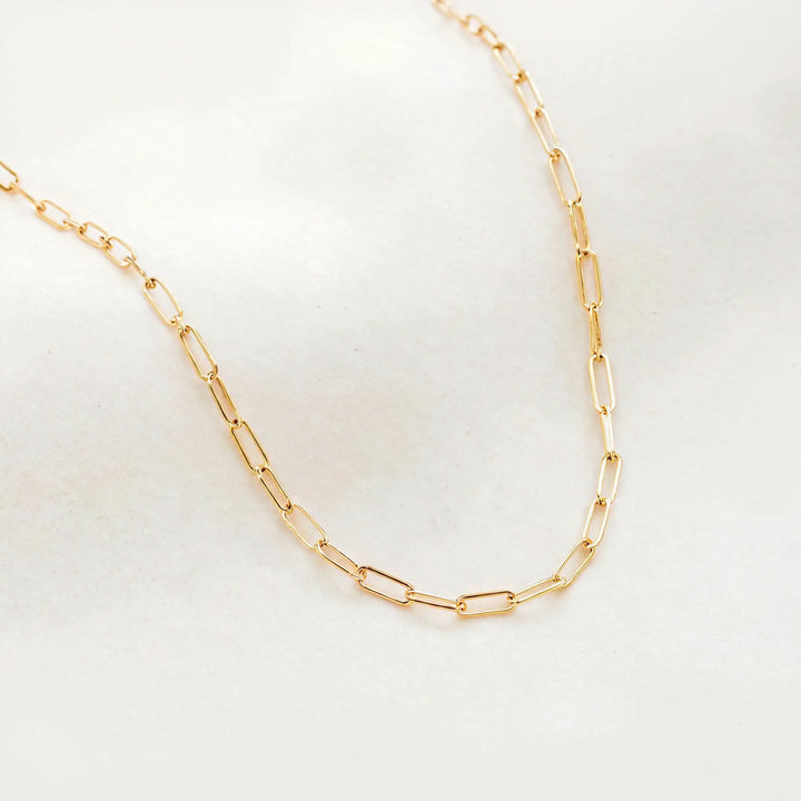 Gold chain necklace on a light gray background
